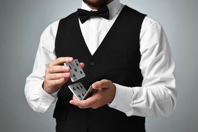 Professional croupier shuffling cards on grey background