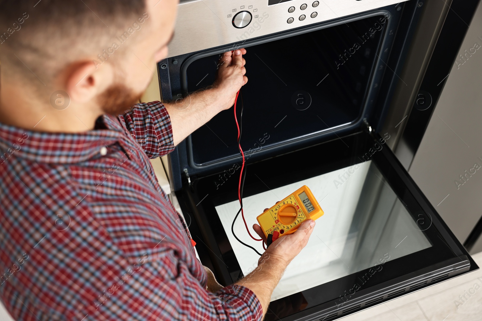 Photo of Repairman testing oven element with multimeter, closeup