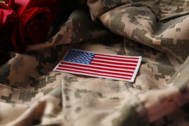 Photo of Veterans day. USA army patch and rose flowers on military uniform, closeup