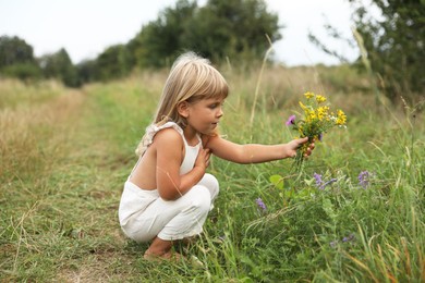 Photo of Cute little girl with flowers at meadow. Child enjoying beautiful nature