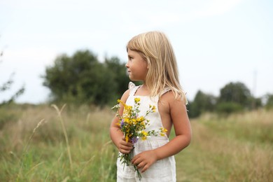 Photo of Cute little girl with flowers at meadow. Child enjoying beautiful nature