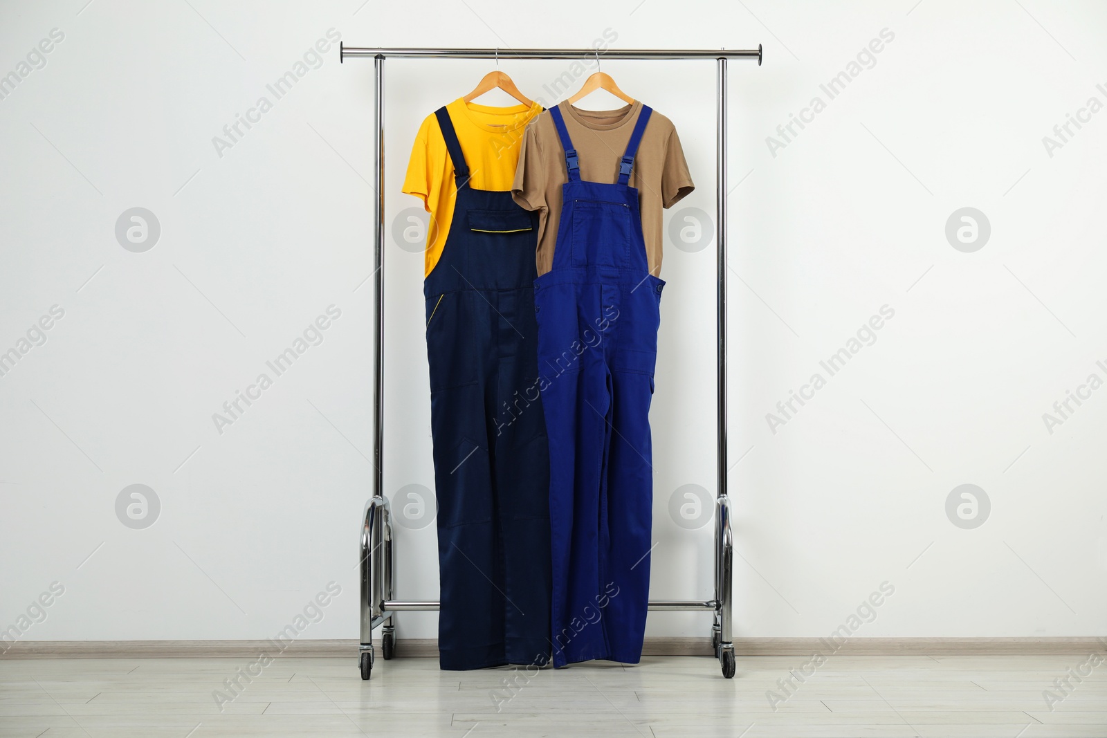 Photo of Workers' uniforms on clothing rack near grey wall indoors