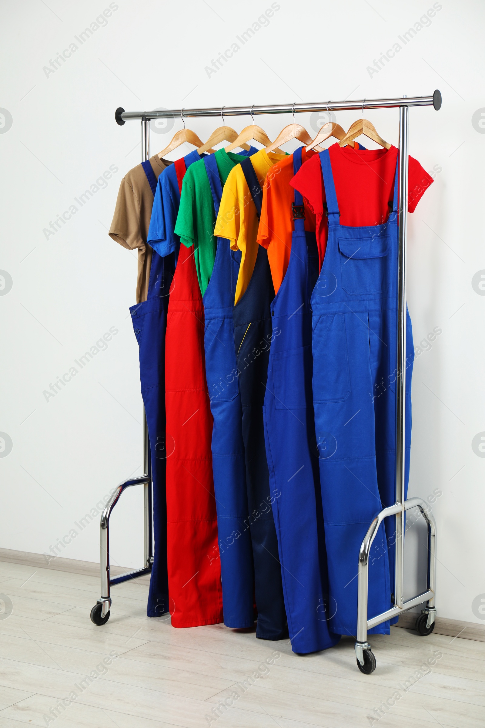 Photo of Workers' uniforms on clothing rack near grey wall indoors