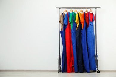 Photo of Workers' uniforms on clothing rack near grey wall indoors. Space for text