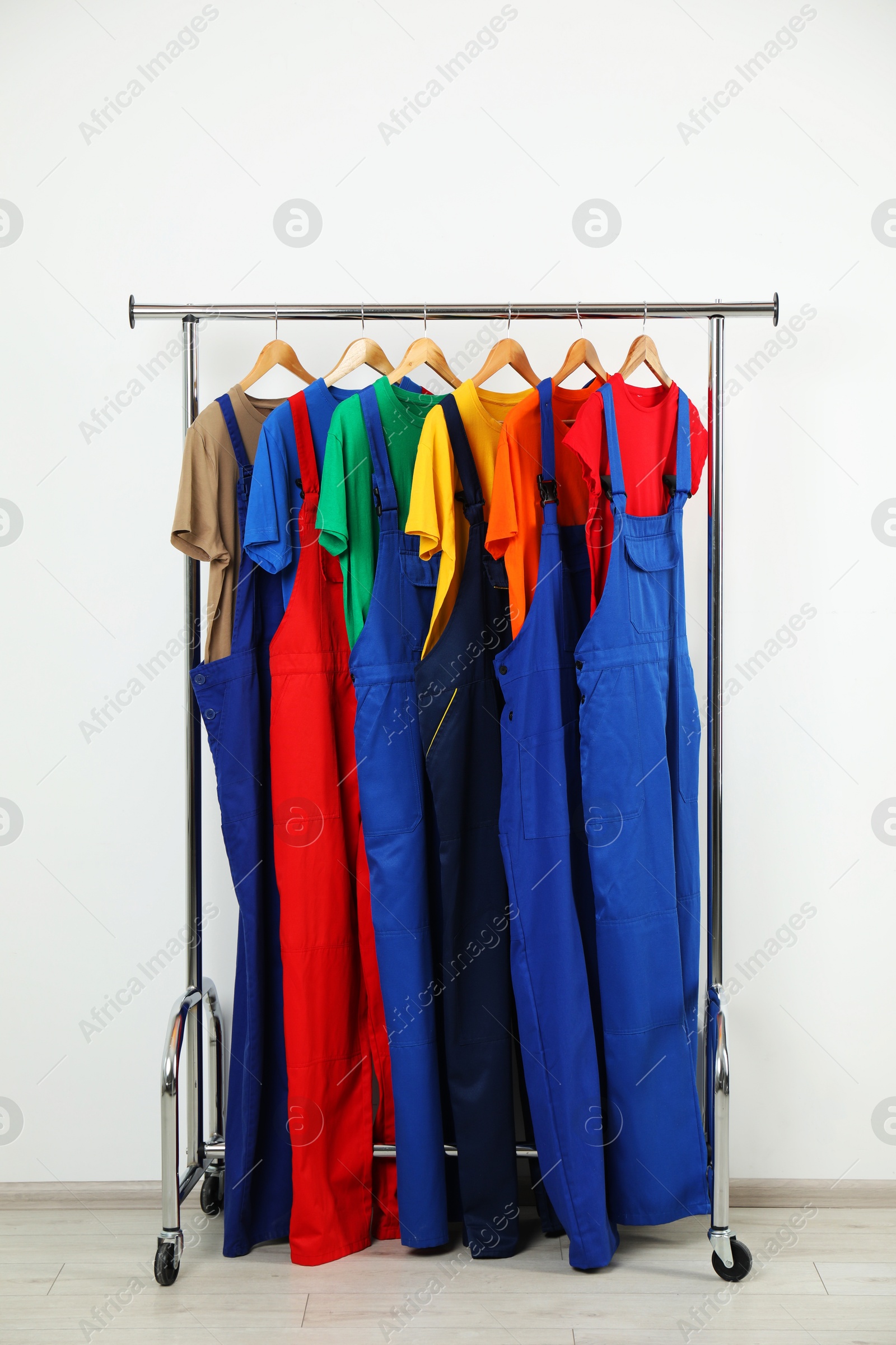 Photo of Workers' uniforms on clothing rack near grey wall indoors