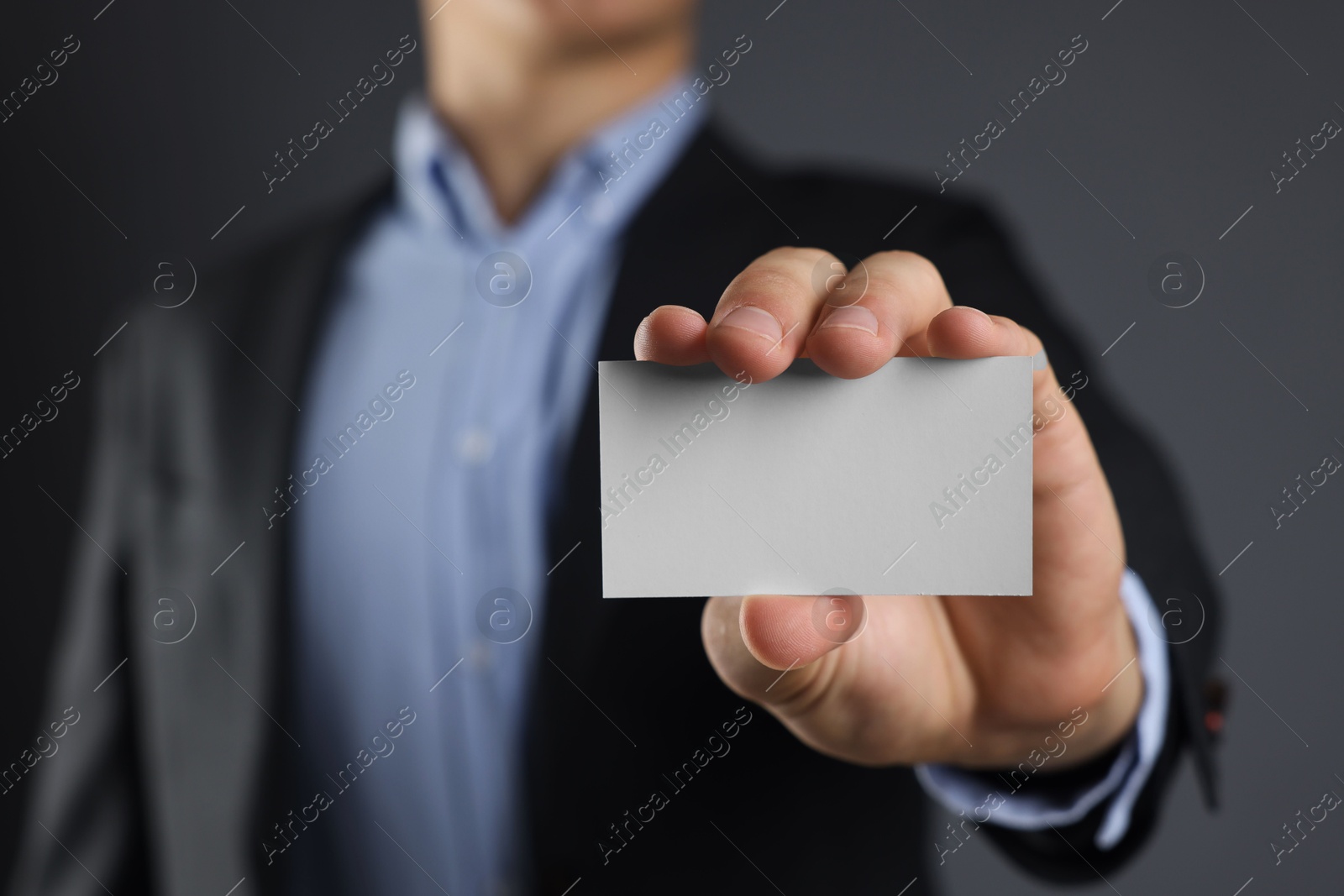 Photo of Man holding blank business card on grey background, closeup. Mockup for design