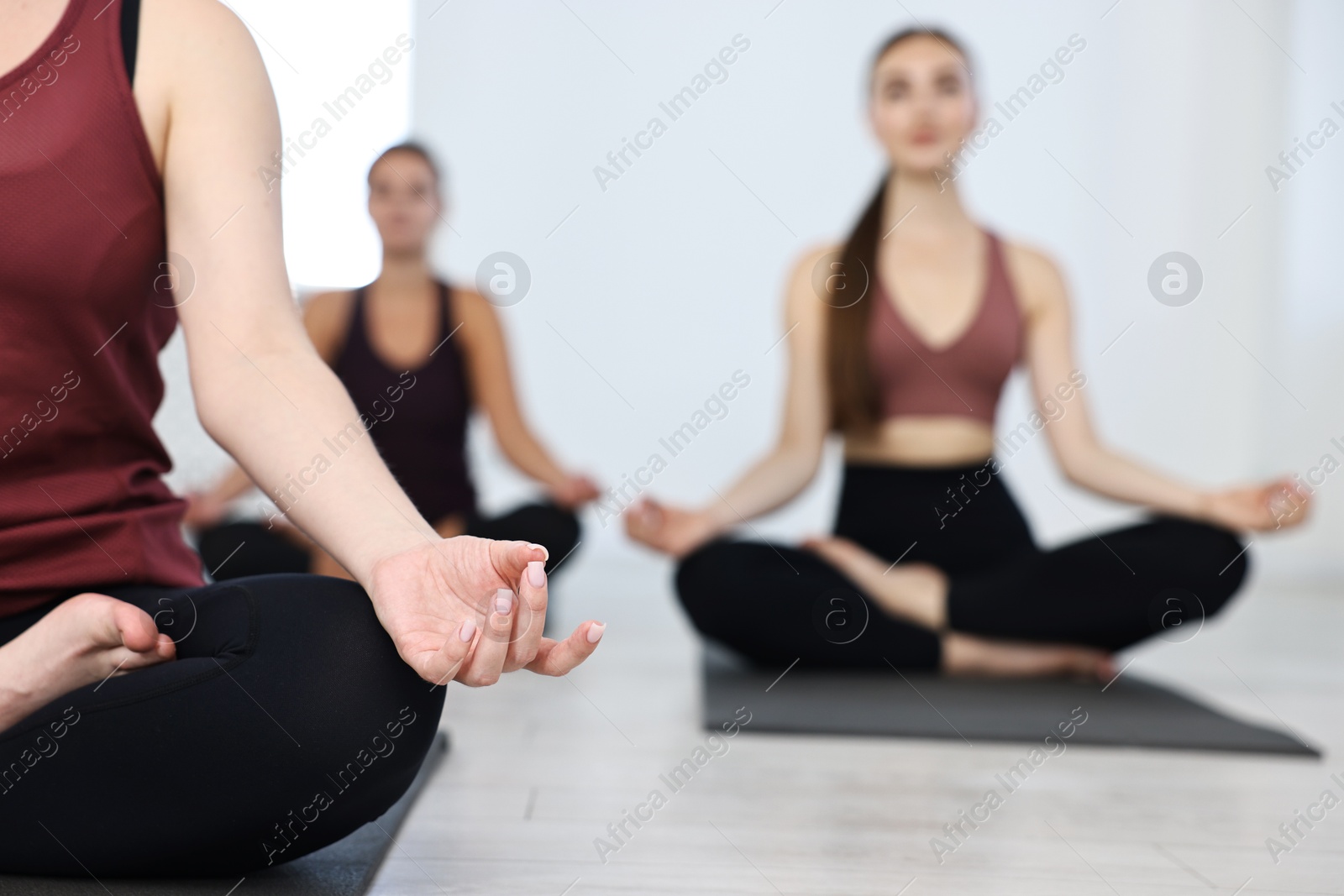 Photo of Group of people meditating on mats in yoga class, closeup