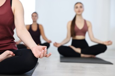 Group of people meditating on mats in yoga class, closeup