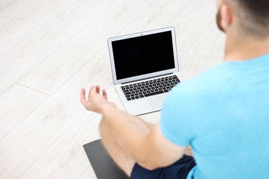 Photo of Man meditating near laptop at home, closeup