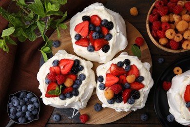 Photo of Pavlova cake (meringue dessert) with whipped cream, fresh berries and mint on wooden table, flat lay