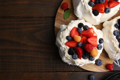 Photo of Pavlova cake (meringue dessert) with whipped cream and fresh berries on wooden table, top view. Space for text