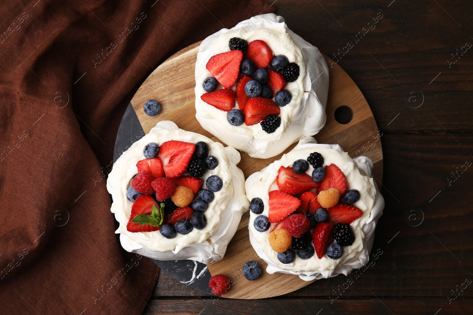 Photo of Pavlova cake (meringue dessert) with whipped cream and fresh berries on wooden table, top view