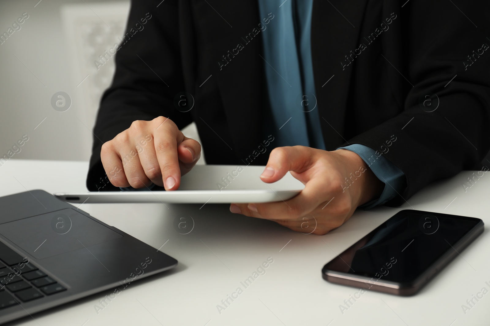 Photo of Businesswoman using tablet at white table indoors, closeup. Modern technology