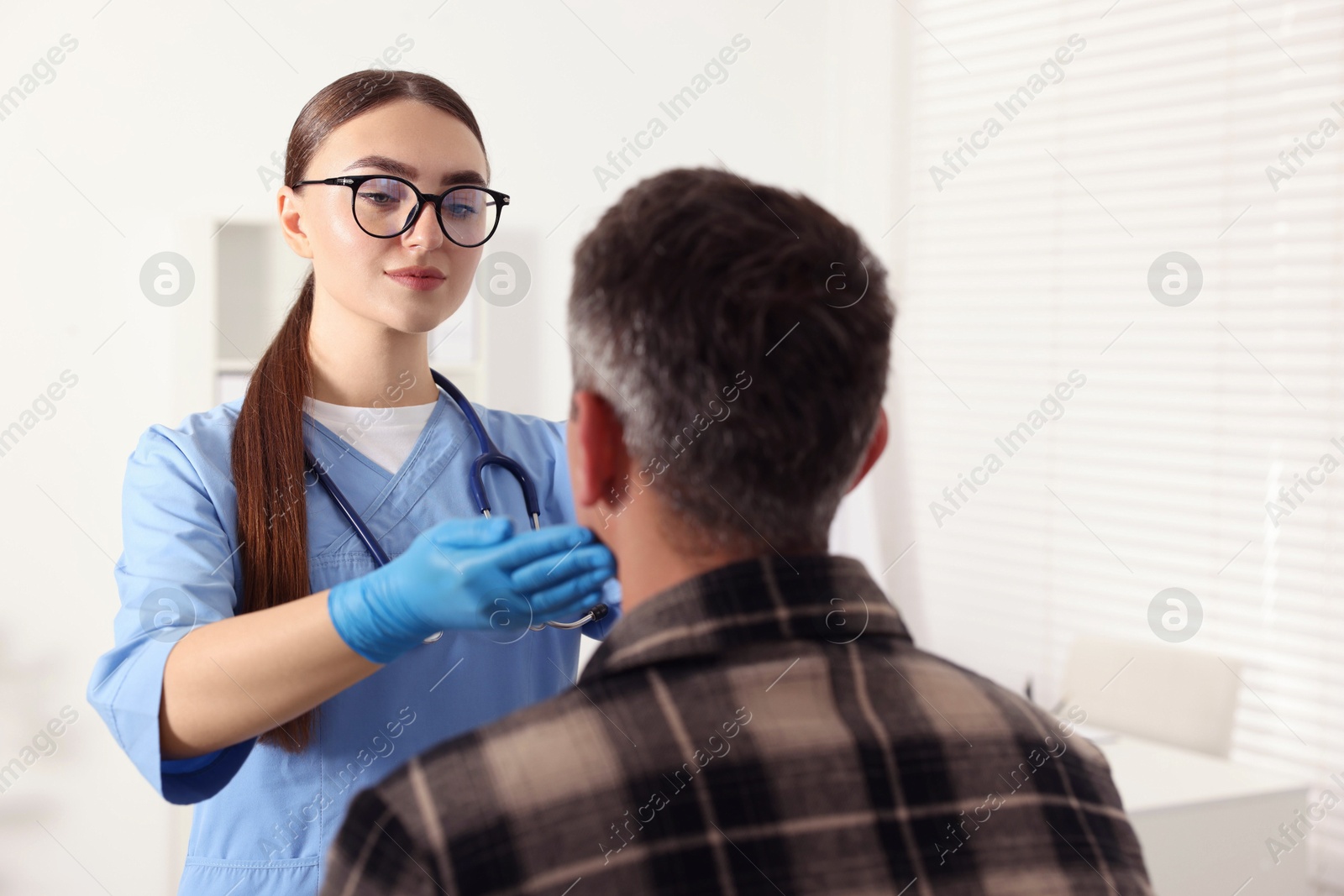 Photo of Doctor examining man's throat in clinic during appointment