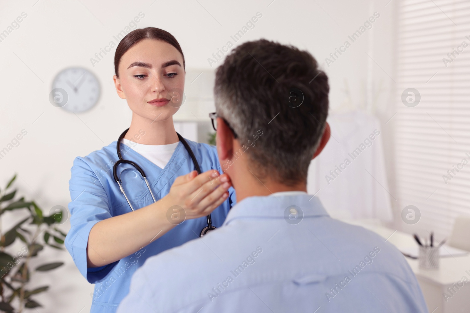 Photo of Doctor examining man's throat in clinic during appointment