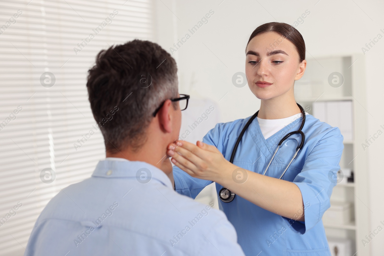 Photo of Doctor examining man's throat in clinic during appointment