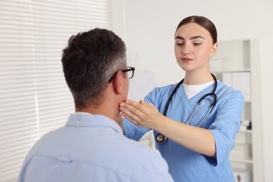 Photo of Doctor examining man's throat in clinic during appointment