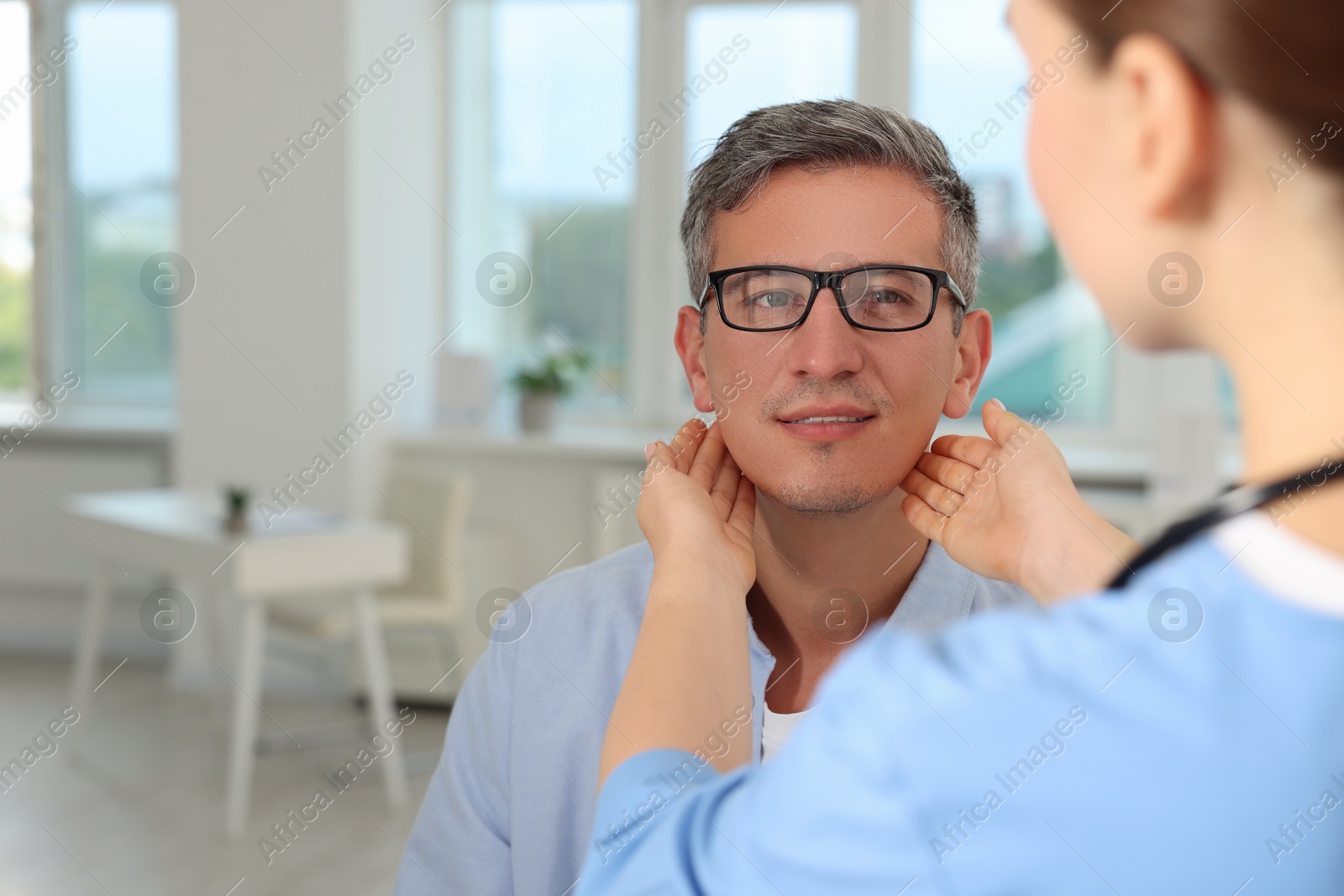 Photo of Doctor examining man's throat in clinic during appointment