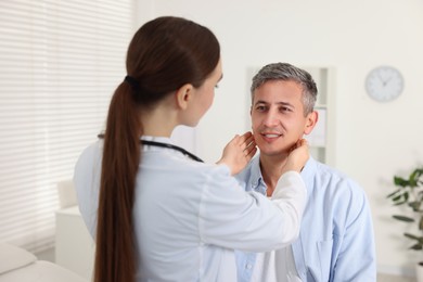 Doctor examining man's throat in clinic during appointment