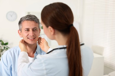 Doctor examining man's throat in clinic during appointment