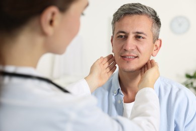 Photo of Doctor examining man's throat in clinic during appointment