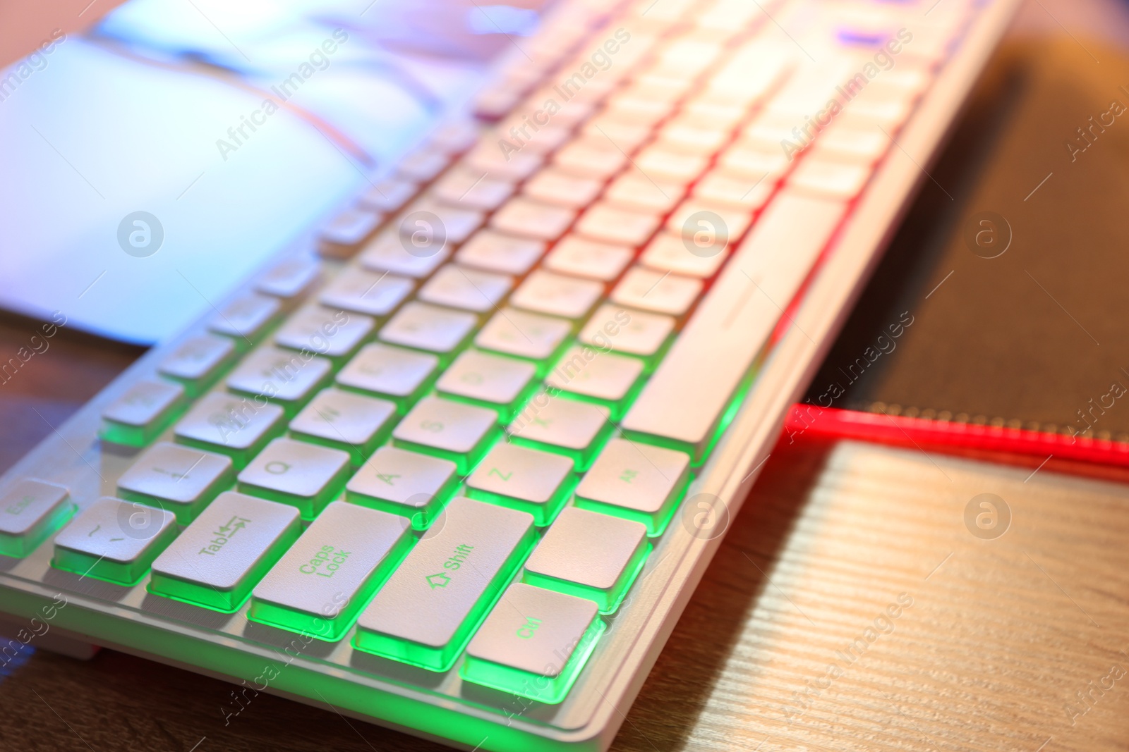 Photo of Computer neon keyboard on wooden table, closeup