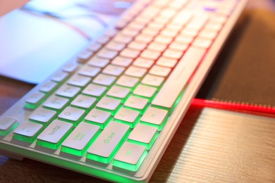 Computer neon keyboard on wooden table, closeup