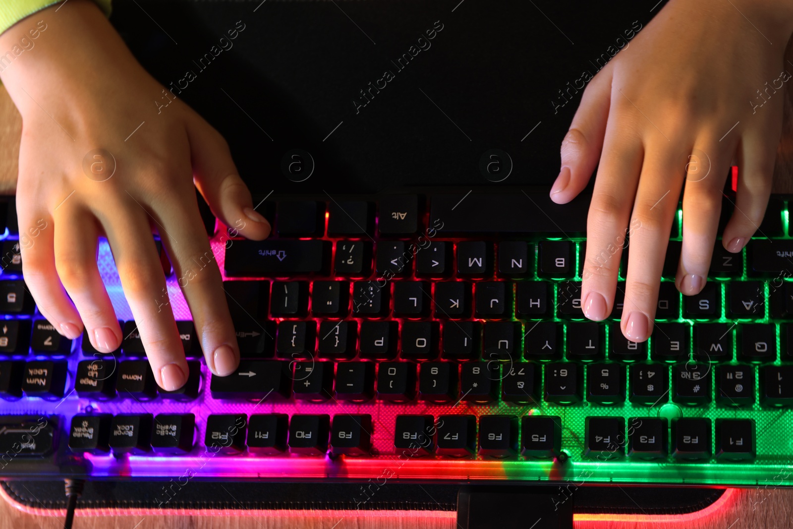 Photo of Girl using computer keyboard at wooden table, above view