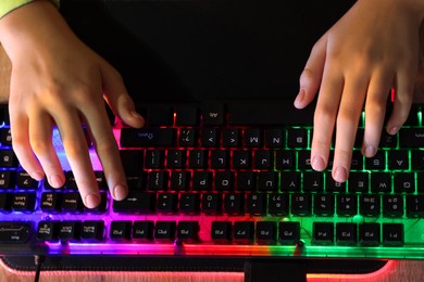 Girl using computer keyboard at wooden table, above view