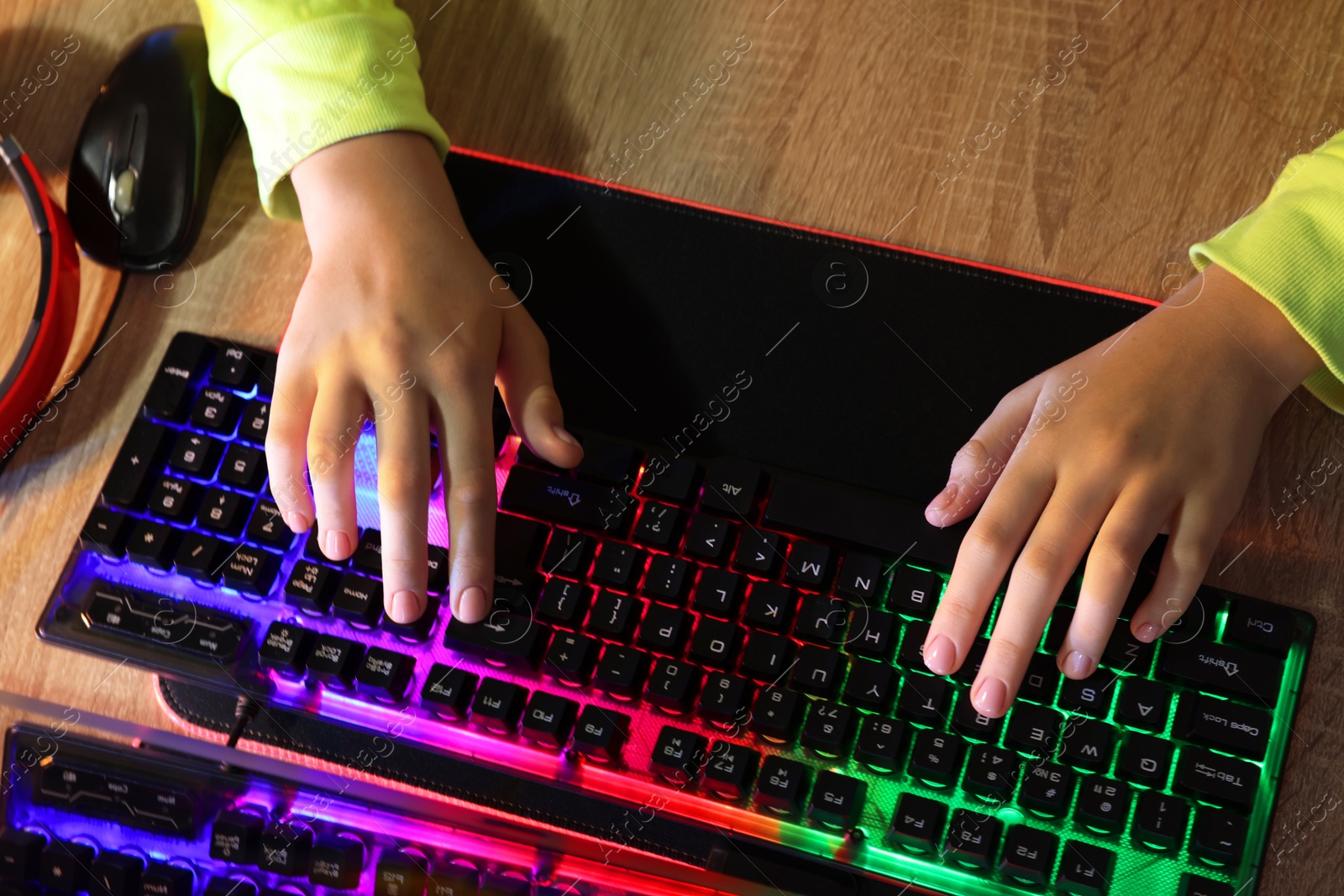 Photo of Girl using computer keyboard at wooden table, top view