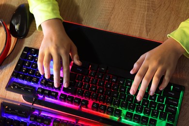 Photo of Girl using computer keyboard at wooden table, top view