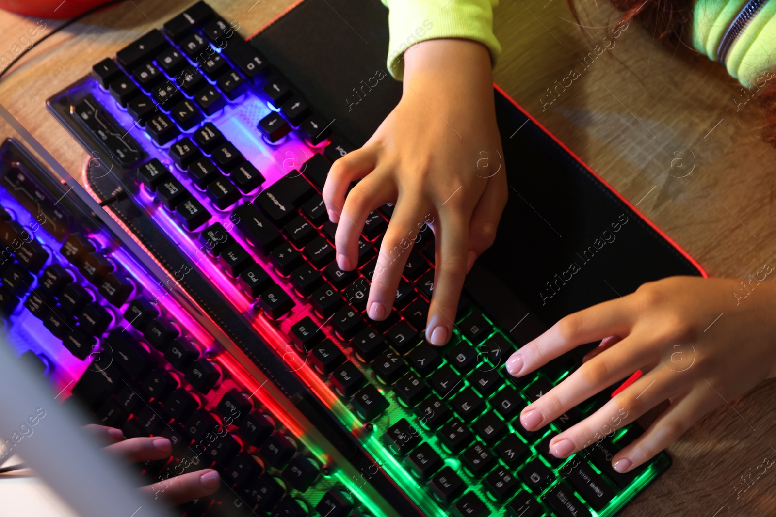 Photo of Girl using computer keyboard at wooden table, above view