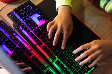 Photo of Girl using computer keyboard at wooden table, above view