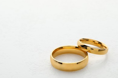 Photo of Beautiful golden wedding ring on white table, closeup. Space for text