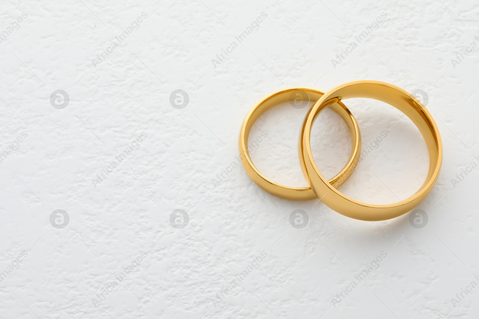 Photo of Beautiful golden wedding ring on white table, space for text