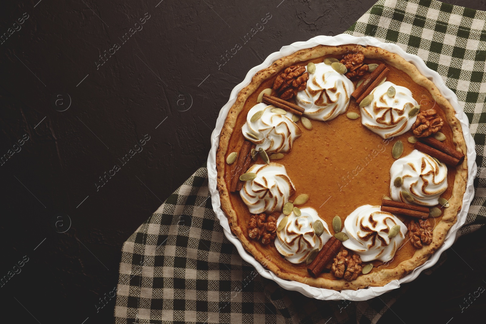 Photo of Delicious homemade pumpkin pie in baking dish on black textured table, top view. Space for text