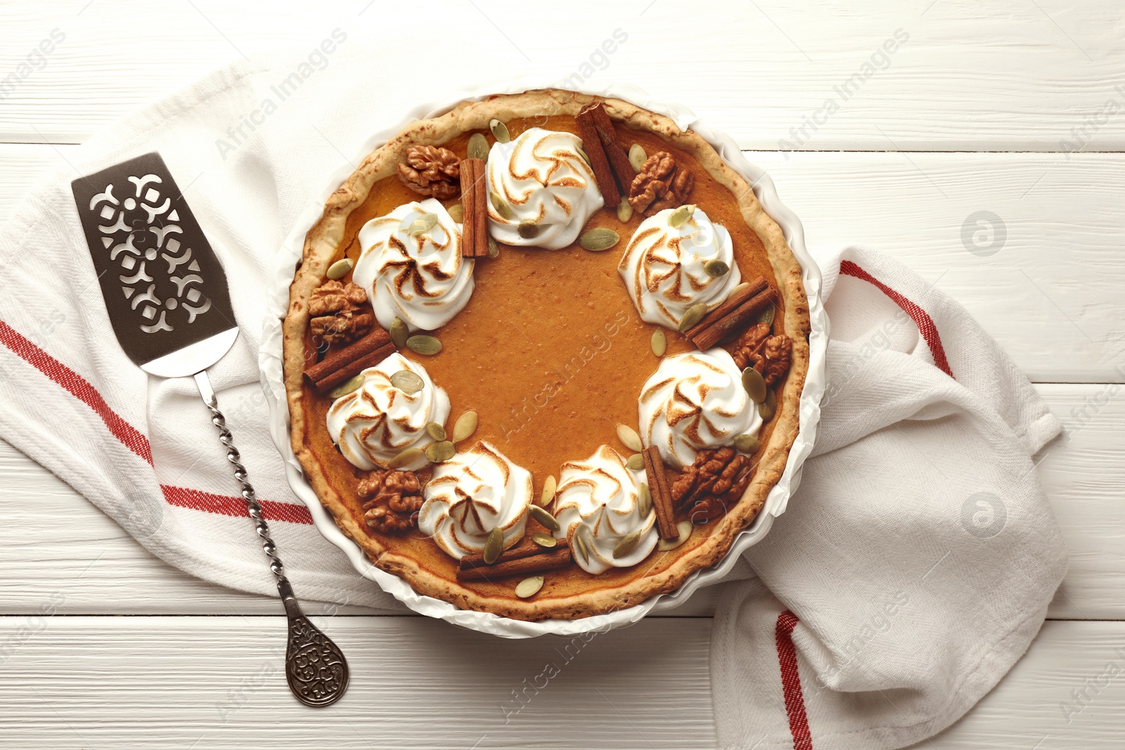 Photo of Tasty homemade pumpkin pie in baking dish and cake server on white wooden table, top view