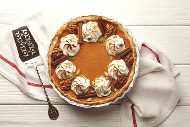 Tasty homemade pumpkin pie in baking dish and cake server on white wooden table, top view