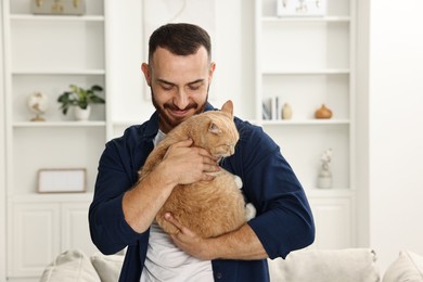 Photo of Man petting cute ginger cat at home