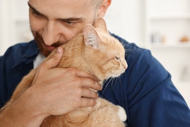 Photo of Man petting cute ginger cat at home