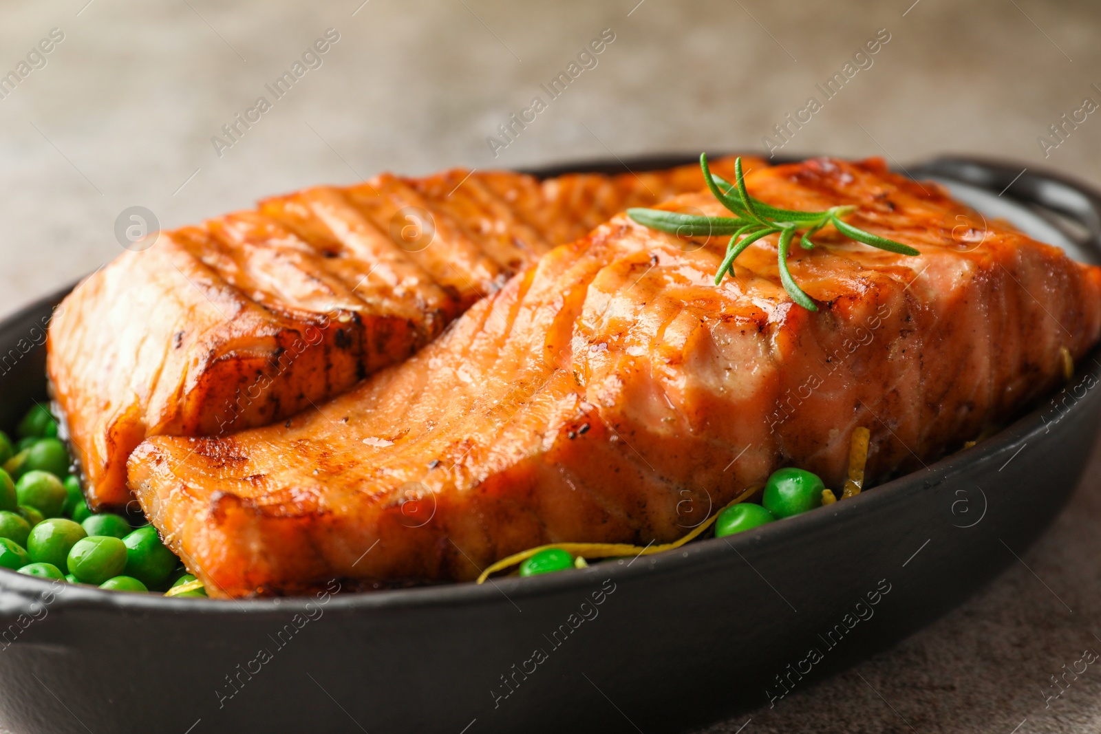 Photo of Delicious grilled salmon fillets with rosemary and green peas in baking dish on grey table, closeup