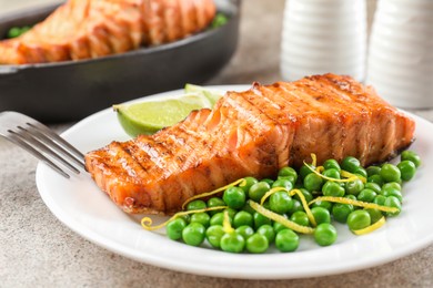 Photo of Delicious grilled salmon fillet served on grey textured table, closeup