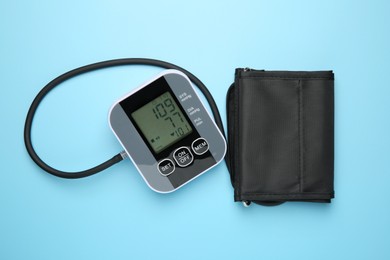 Photo of Blood pressure measuring device on light blue background, top view