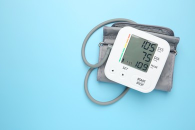 Photo of Blood pressure measuring device on light blue background, top view. Space for text