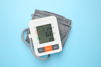 Photo of Blood pressure measuring device on light blue background, top view