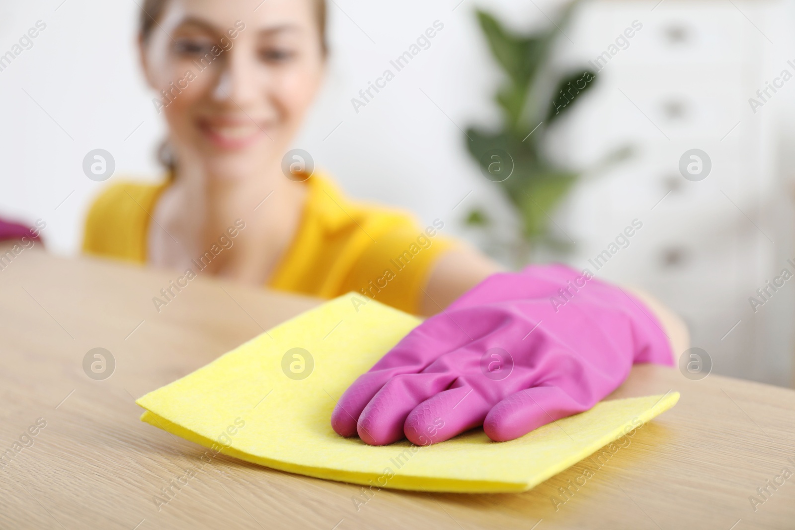 Photo of Woman cleaning table with rag at home, selective focus