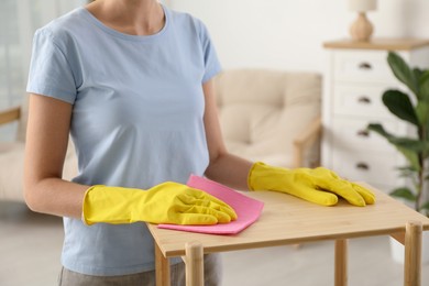 Photo of Young woman cleaning wooden shelf with rag at home, closeup