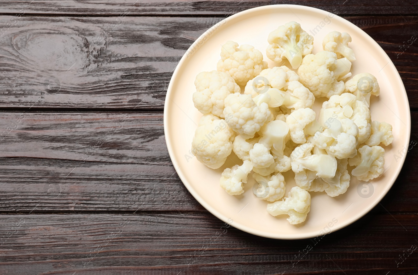 Photo of Tasty cooked cauliflower on wooden table, top view. Space for text