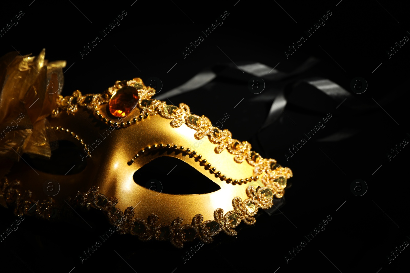 Photo of Beautiful golden carnival mask on black background, closeup