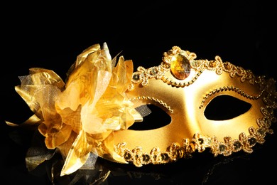 Photo of Beautiful golden carnival mask on black background, closeup